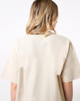 Model wearing a beige shirt with a white printed reverse BB logo on a white background