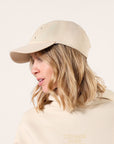 Side view of a person wearing a neutral 'I I II I' dad cap with black embroidery