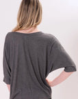 Back-view of a model wearing a gray one-size t-shirt with batwing-style draped short sleeves on a white background