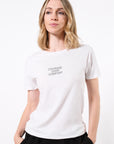 Model wearing a white t-shirt with 'Courage Over Comfort' printed in black with black sweatpants in front of a white background