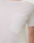 Close-up view of a white, printed tonal t-shirt with a pocket that says 'Personal." on a plain background