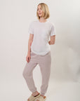 Model wearing a white, tonal pocket t-shirt with 'Personal." written on the pocket located on the left chest and Birdiebee stone sweatpants on a plain background