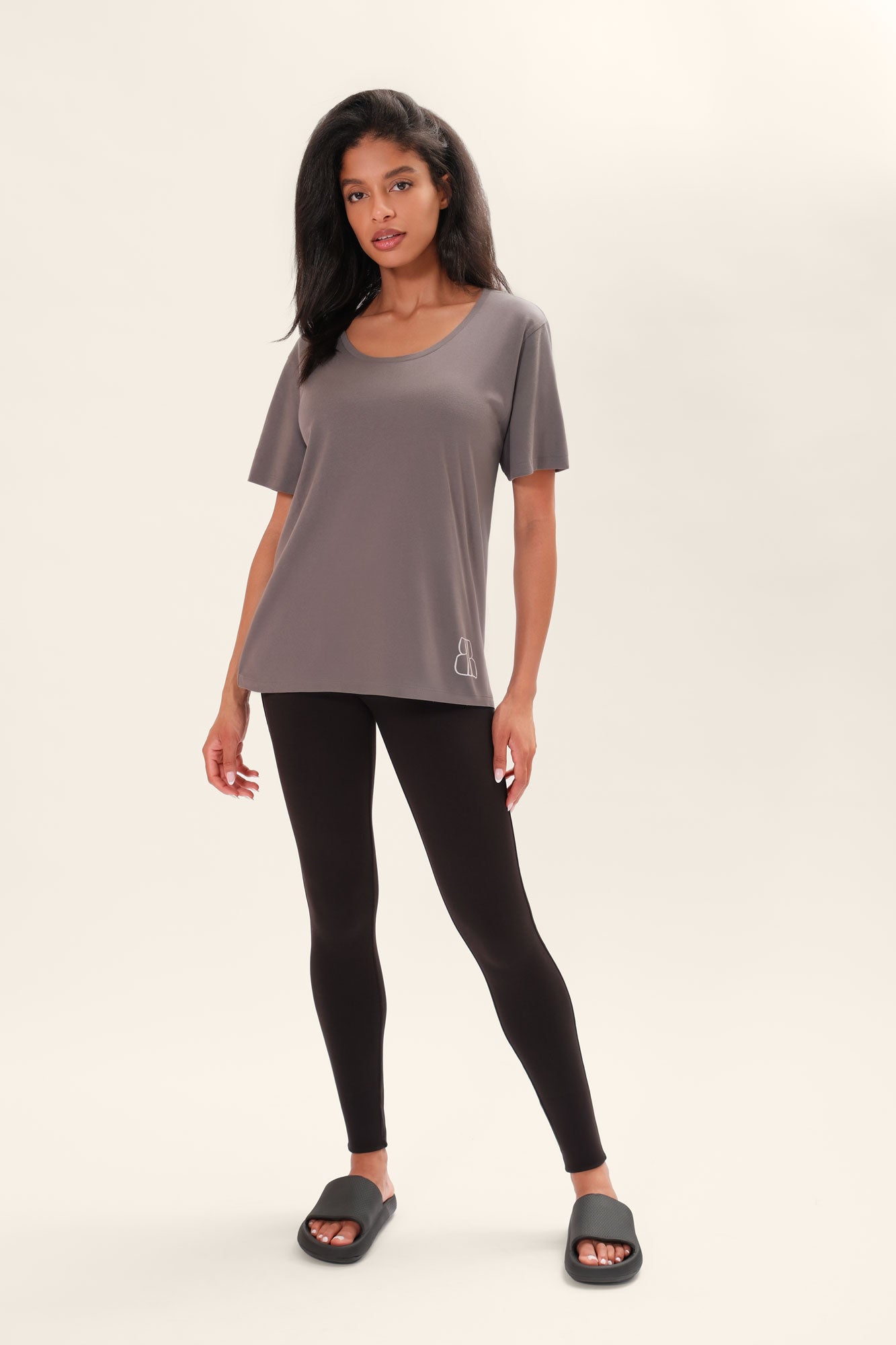Model wearing a one-size gray t-shirt with a BB logo on the lower left corner and black leggings on a white background