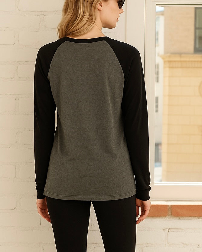 Back view of model wearing sporty raglan tee that is gray and black looking out the window